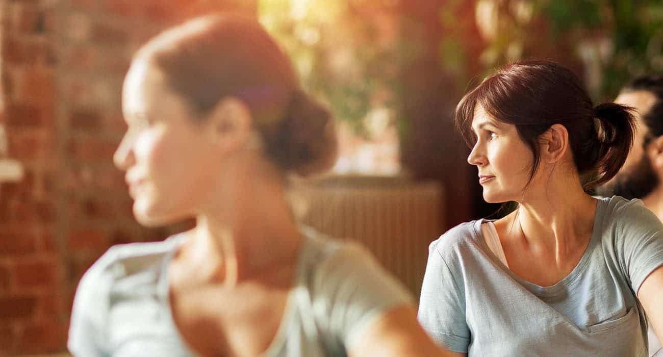 A family of four sits around a dinner table, smiling and talking while enjoying a meal together. Plates of food and glasses of water are on the table in a bright, modern dining area.